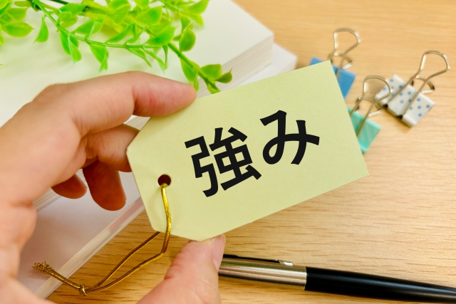 強みの文字列が書かれた札を持つ手